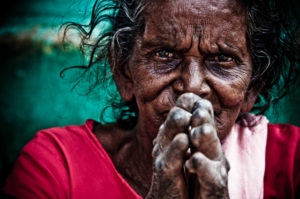 a woman at embrace a village puts her hands together in a prayer fashion