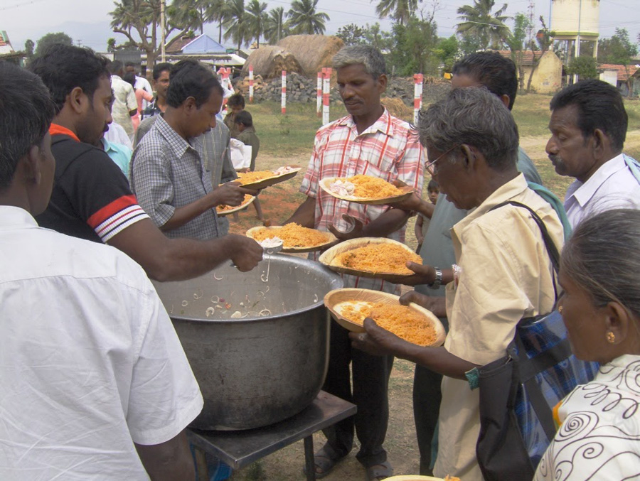 men gather around a hot meal at embrace a village
