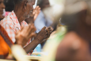 a man prays at a meeting at embrace a village