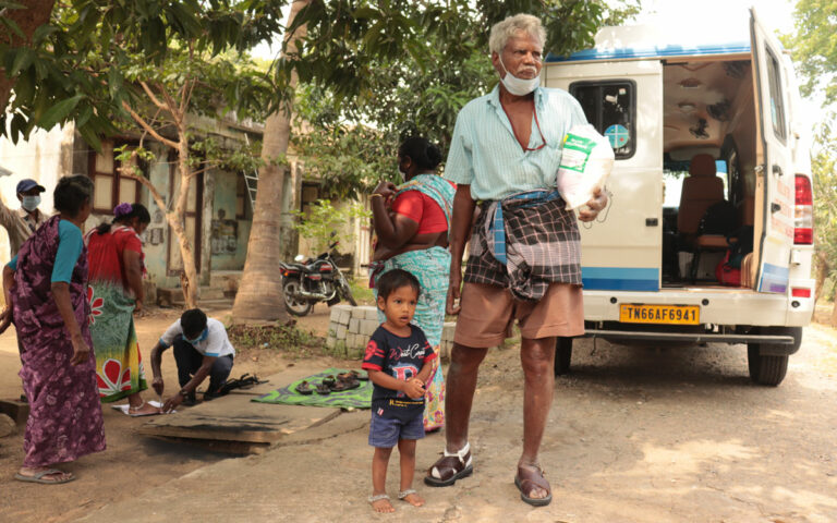 Man stands holding bag of rice